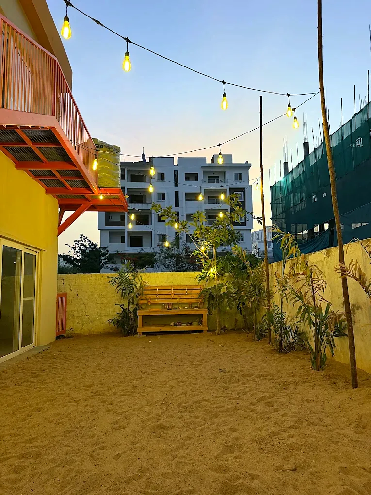 The sand play yard at dusk under strings of warm lights