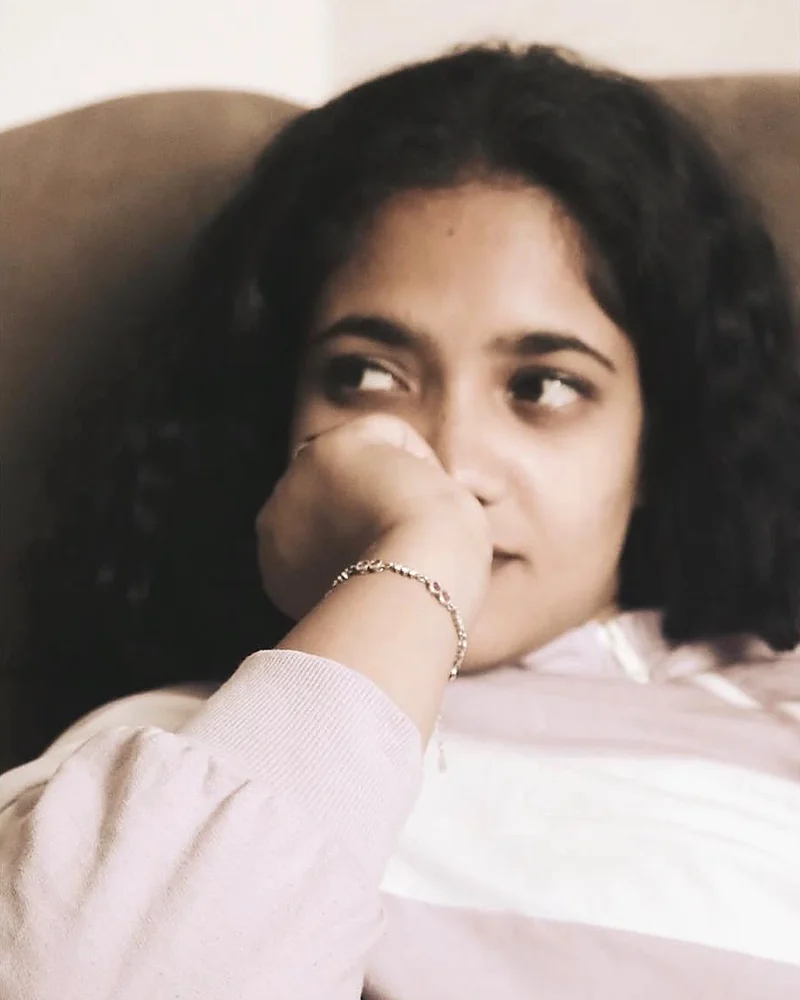 Shravika Bheemreddy, resting her chin on her hand and smiling as she looks to the side