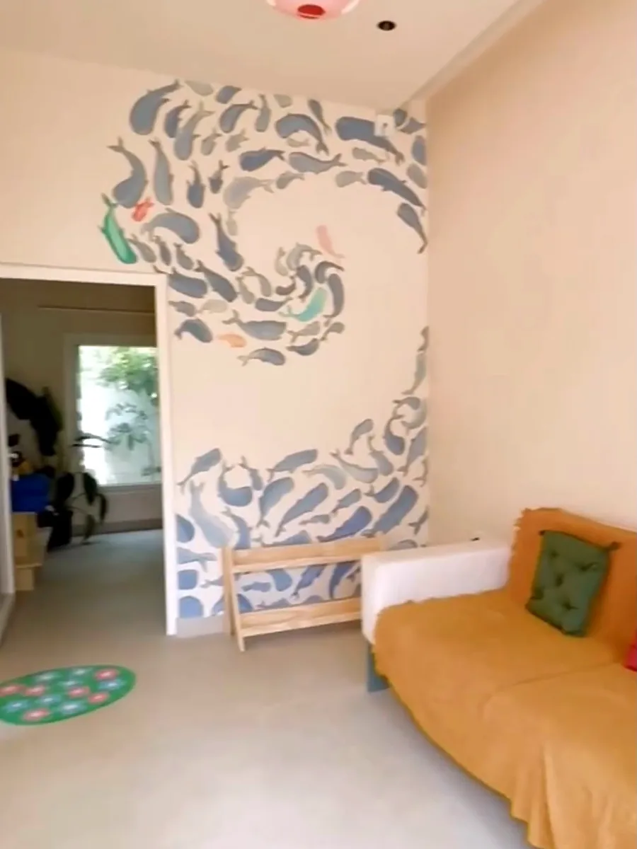 A quiet room with a wall mural of swirling blue whales and a soft mustard sofa